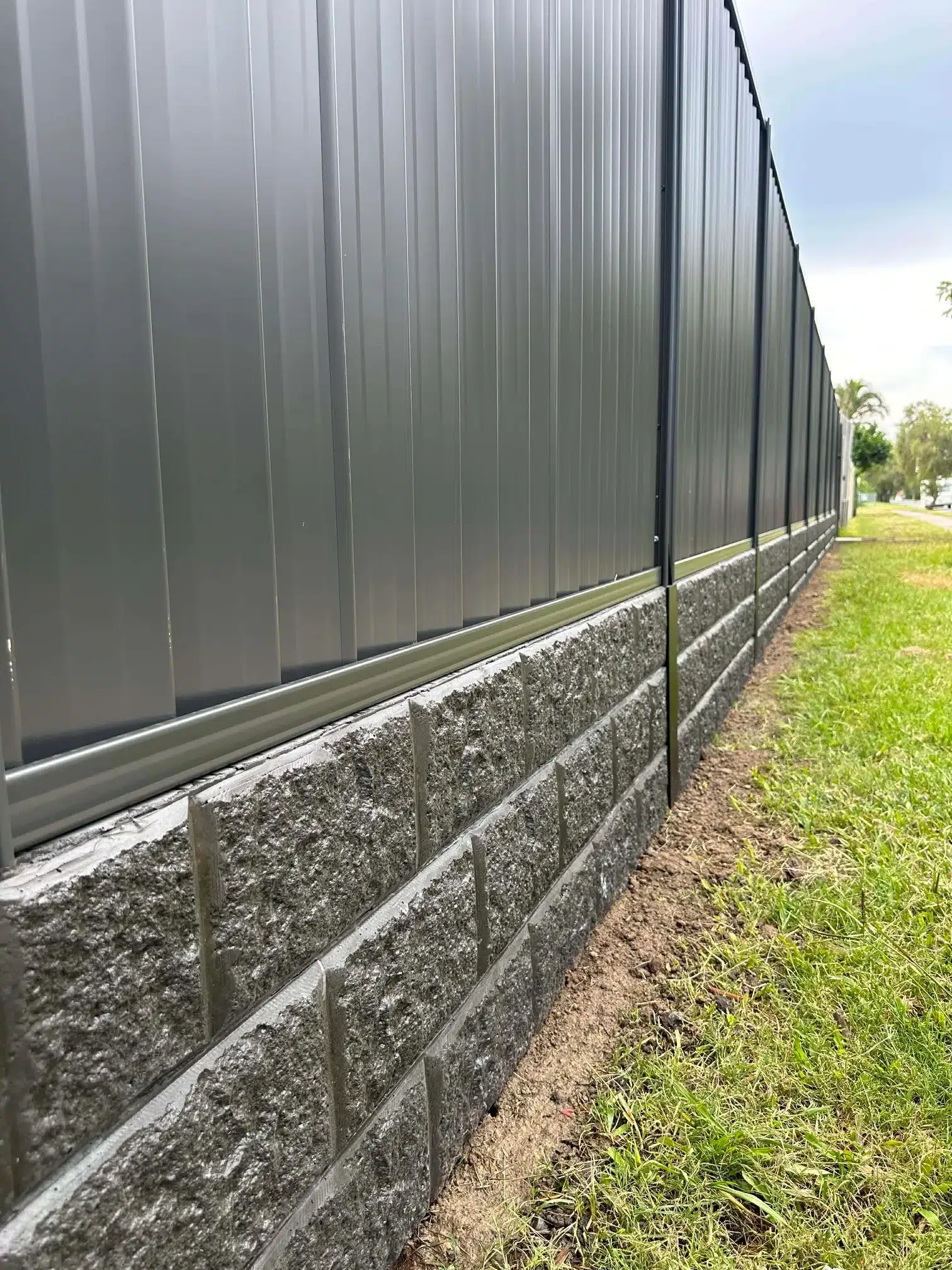Corrugated fencing above a modular retaining wall