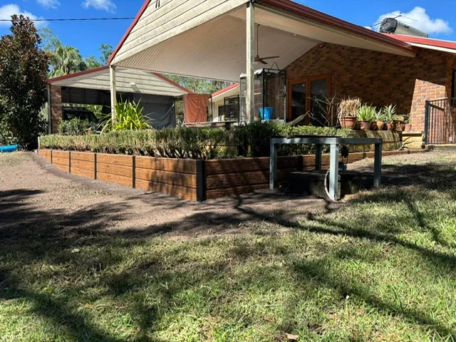 Paved outdoor entertaining area framed by timber retaining walls