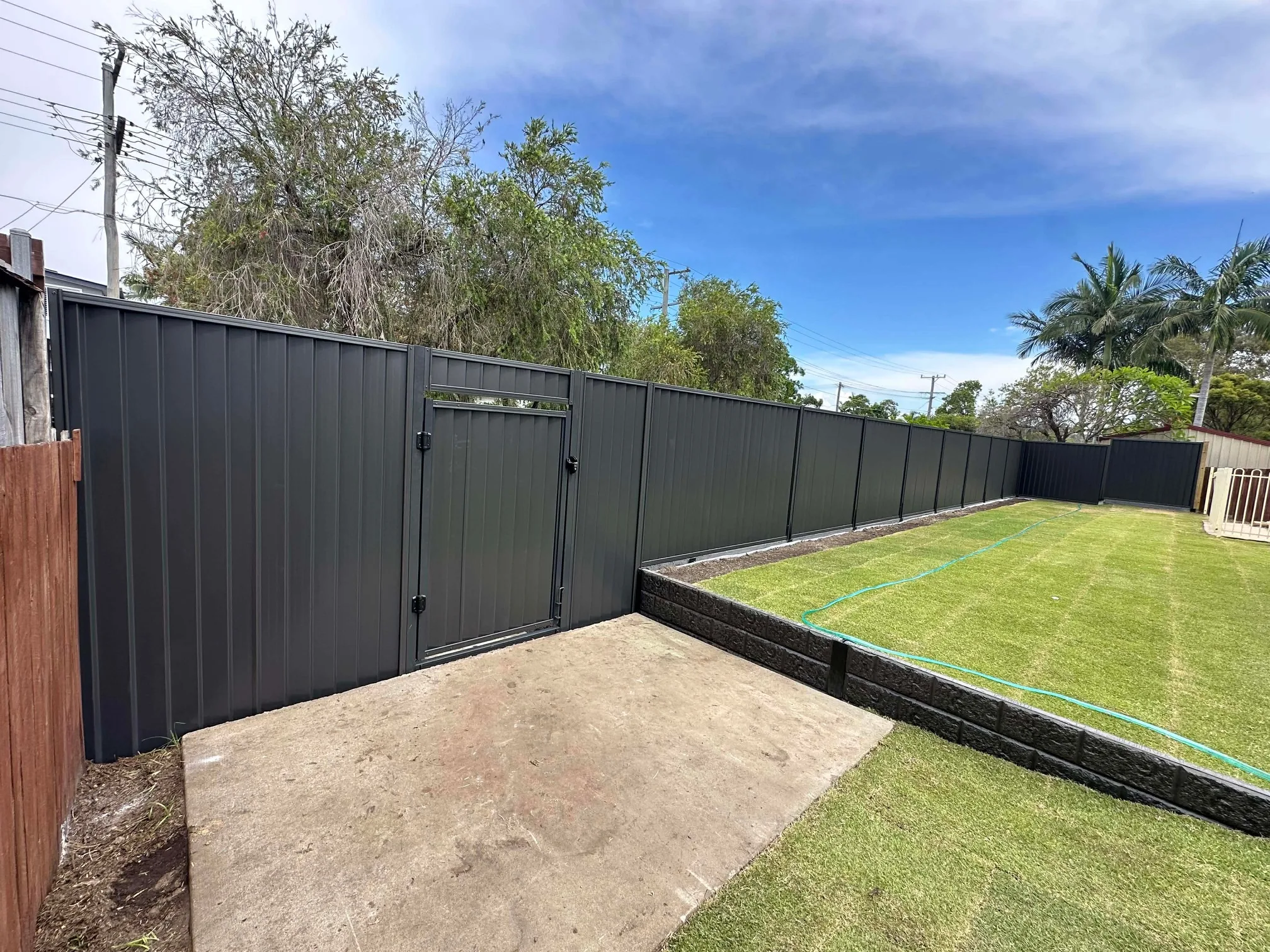 Corrugated fence and retaining wall along a new lawn