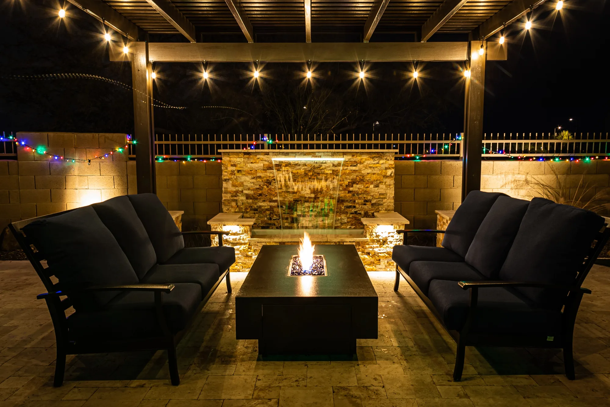 Fire pit table under a pergola with feature lighting