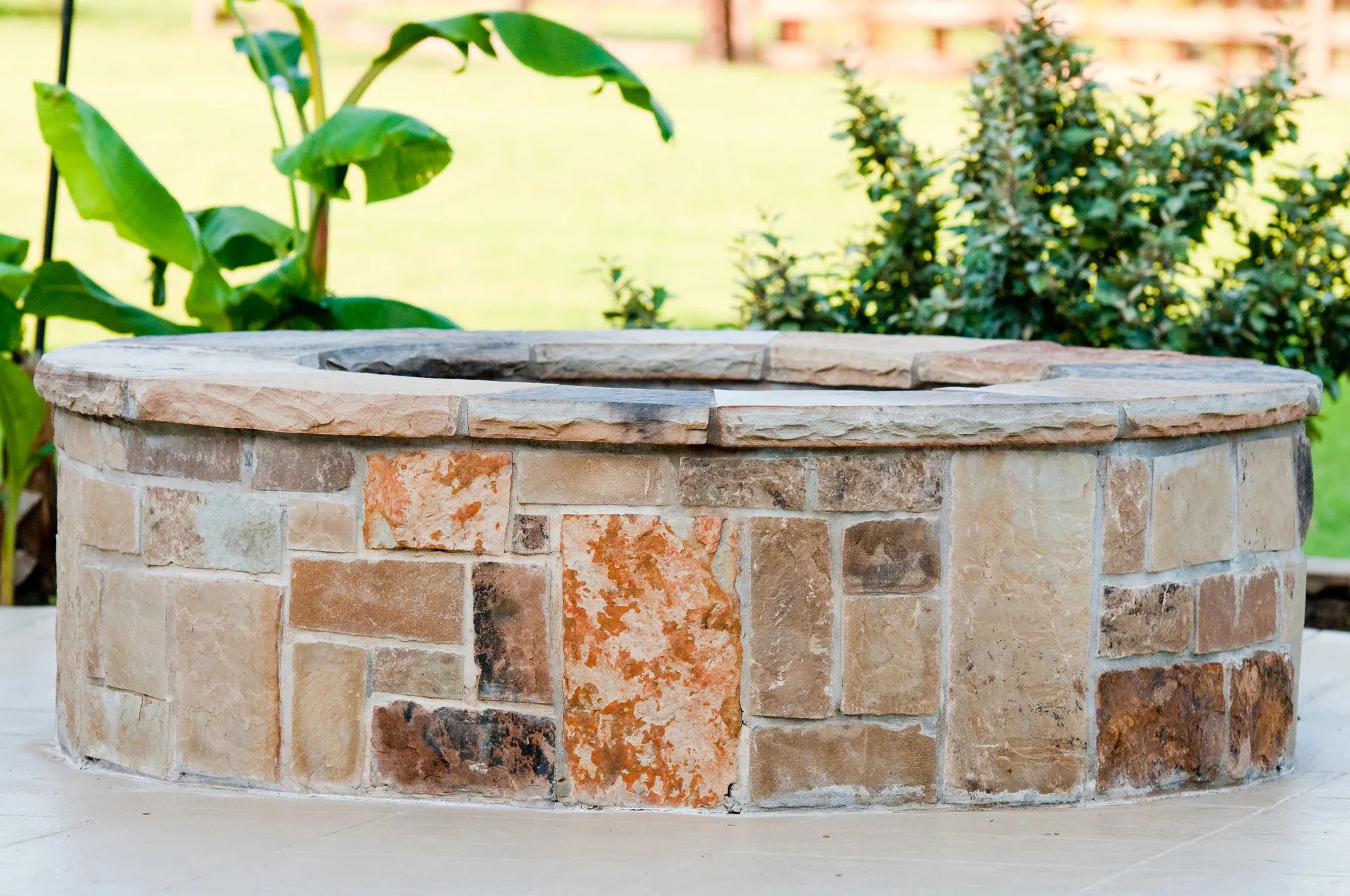 Stone-clad fire pit surround with established planting