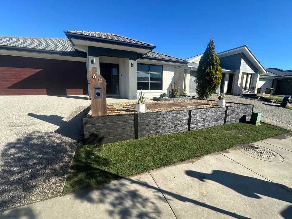 Landscaped front yard with a stone retaining wall and new turf in Croydon