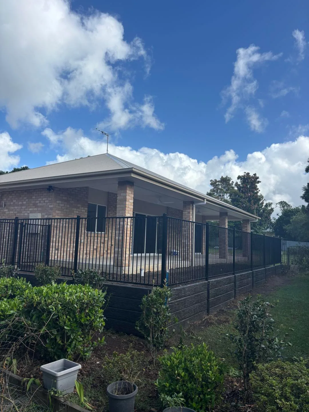 Front yard with black fence and retaining wall